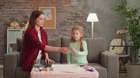 Girl Gives Brush to Elder Sister Preparing for Ebru Drawing