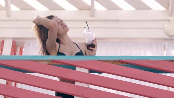 Girl on Summer Beach Touching Her Hair Drinking Cocktail 1