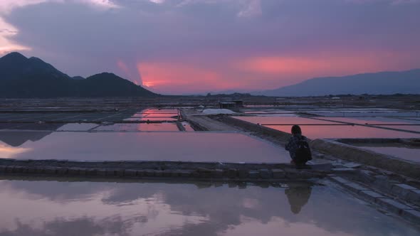 Silhouette of solo tourist sitting amidst peaceful and silent environment of vast endless salt field