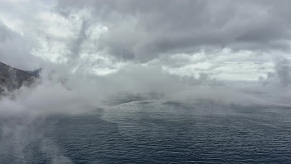 Backward Aerial Tracking Shot of Ocean Waters and Fog Covering the Frame