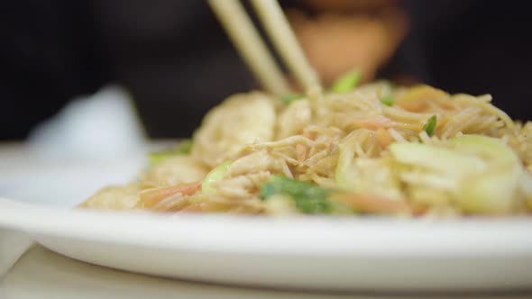 A Person Eats an Asian Meal with Chopsticks - Closeup