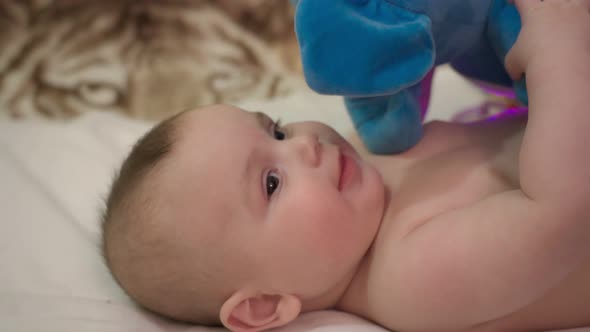 Newborn Baby Boy Lying Down Biting and Playing with His Toy Plushy in a Cute Close Up