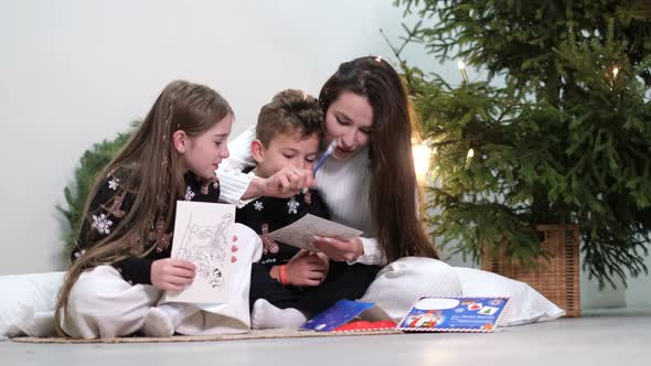 Young Mother with Daughter and Son Near the Christmas Tree