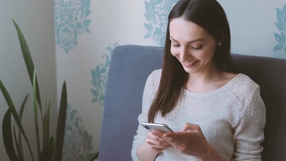 Woman Using Mobile Phone Sitting on the Couch