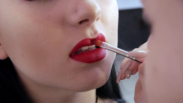 Bright Lip Makeup Big Beautiful Lips are Painted with Red Lipstick with a Special Brush in a Beauty