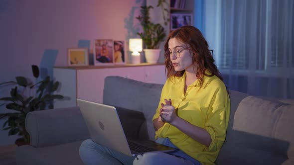 Woman with Glasses Talks with Friends Online Using Video Camera on Laptop and Internet While Sitting