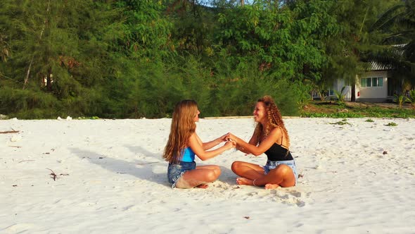 cheeky girls playing hand games on the beach. Thailand sandy coast