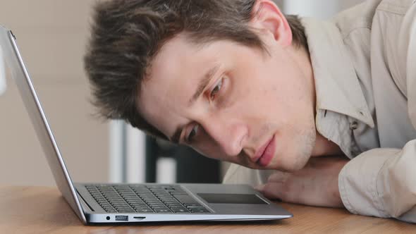 Sad Tired Sleepy Caucasian Millennial Man Office Worker Lays Head on Laptop Keyboard Falling Asleep