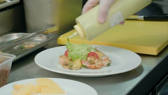 Chef's Male Hands Adding Sauce and Spices To Fresh Salad with Shrimps