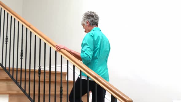 Senior woman climbing upstairs with walking stick