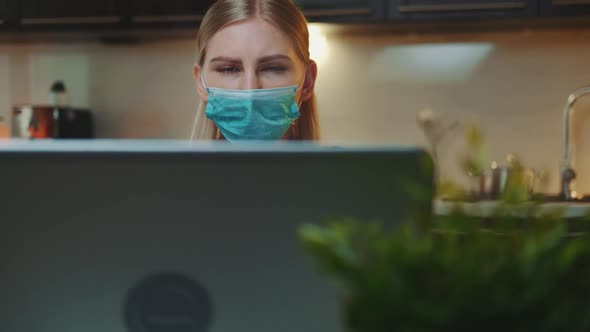 Front View of Computer Monitor and Woman in Medical Mask Reading Something on It