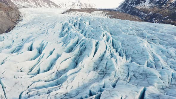 Drone Over Ice In Large Glacier At Foot Of Mountains