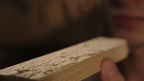 A Man Blows Off Dust From the Wood Element. Close Up