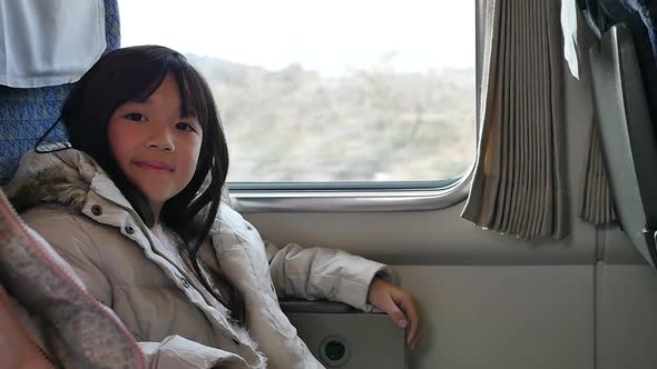 Little Asian Girl Looking Through Window. She Travels On A Train