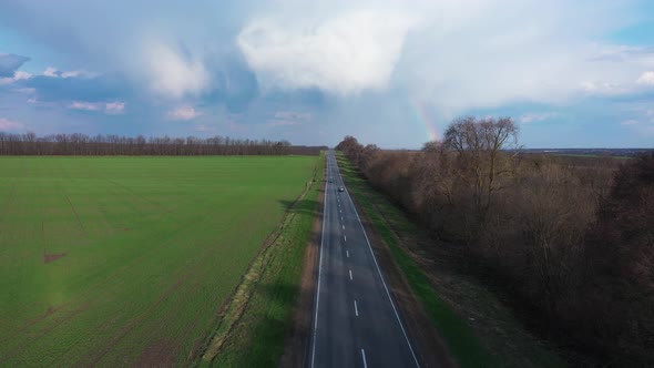 Scenic Road During a Vibrant Sunny and Cloudy Summer Morning With Rainbow