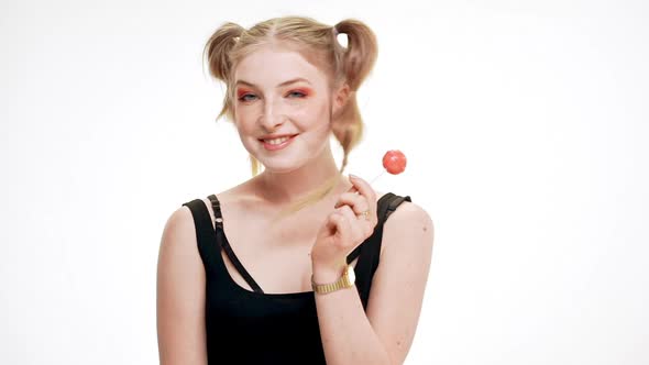 Young Beautiful Girl Dancing Smiling Eating Chupa Chups Over White Background