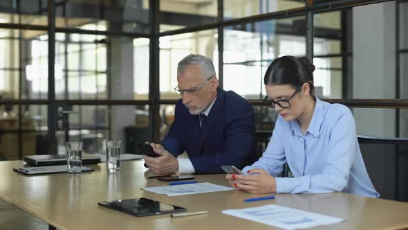 Two Office Managers Typing Email on Smartphones Waiting for Business Clients