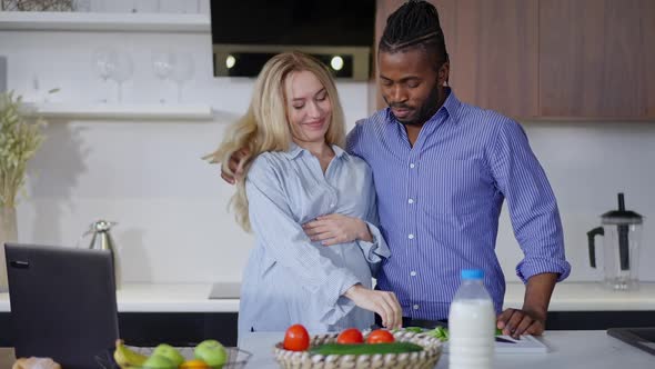 Pregnant Caucasian Woman Tasting Organic Ingredients for Healthful Salad As African American Man