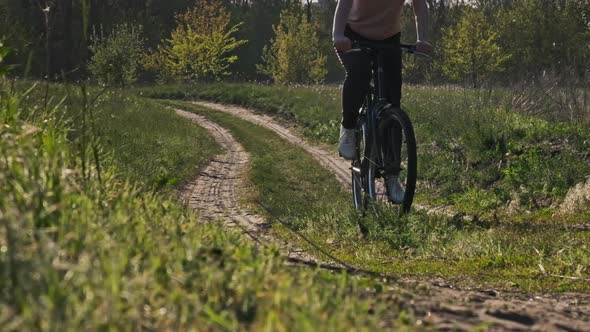 Young Woman on Bicycle Rides Along Green Forest Path in Summer Day Slow Motion