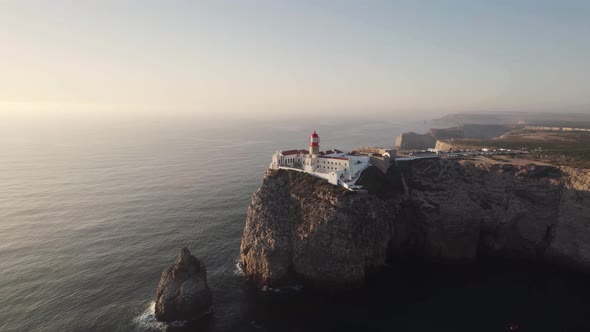 Aerial slow orbit Cabo de Sao Vicente Lighthouse on the cliffside - Sagres