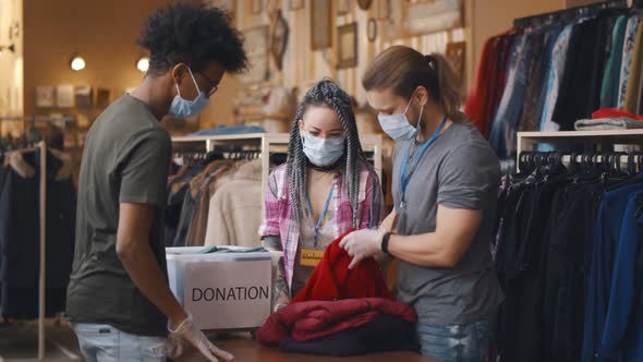 Young African Man Wearing Safety Mask Donating Old Clothes in Charity Organization