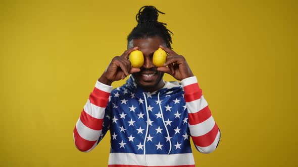 Portrait of Joyful Handsome Confident African American Man Holding Lemons at Eyes and Juggling