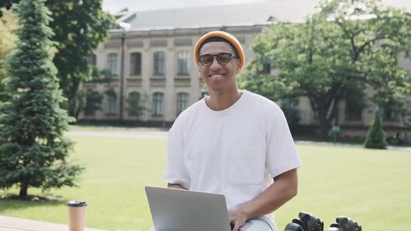 Closeup of a Young African American International Student Sitting Studying Outdoor on a Banch