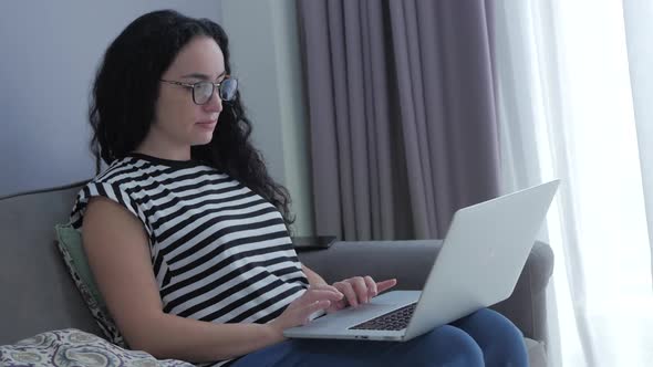 Woman Typing on Laptop Sitting on Sofa at Home, Businesswoman Sits at Home Types on Smartphone