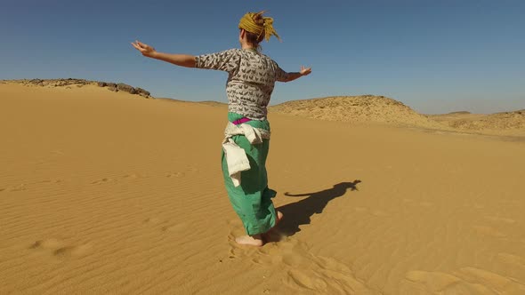 Happy woman dancing barefoot in desert, Egypt