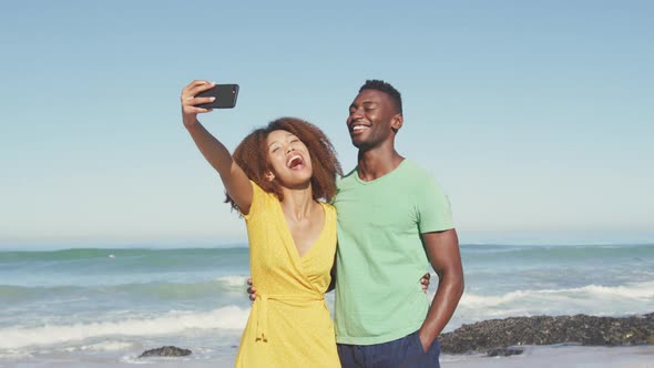 African American couple taking a selfie seaside