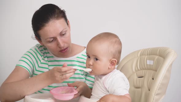 A Newborn Sitting On A High Chair Is Fed Porridge Hd 2