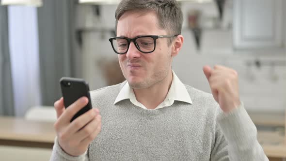 Young Man Reacting To Loss on Smartphone