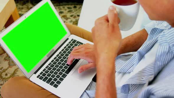 Man using laptop while having coffee in living room at home 4k