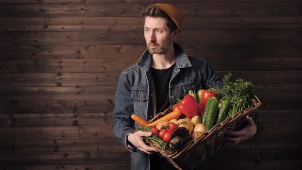 Young Farmer Holds a Wicker Basket with Fresh Organic Vegetables