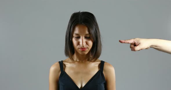 an accusing hand points to a woman's face, humiliating her