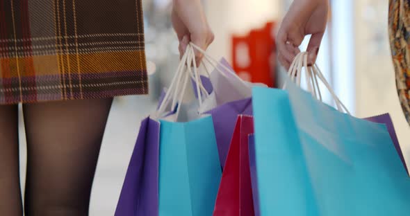 Close Up Two Women Holding Shopping Bags While Walking in Shopping Mall