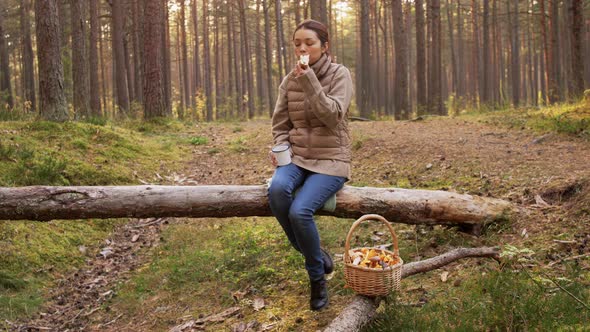 Woman with Mushrooms Drinks Tea and Eats in Forest