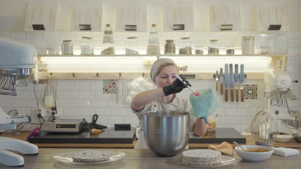 Woman in Uniform and Black Gloves Stand in the Modern Kitchen with Many Kitchen Utensils Around and