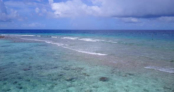 Wide angle flying copy space shot of a sandy white paradise beach and aqua blue water background in 