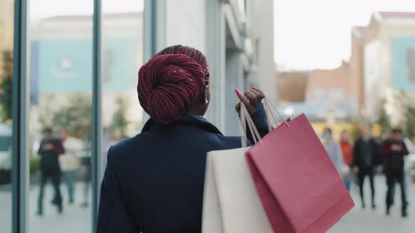 Back View African American Girl Shopper Shopaholic Consumer Walking on City Street Near Building