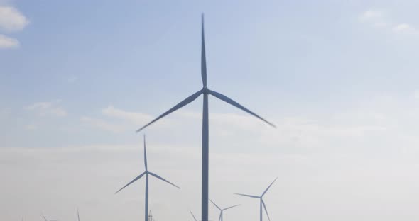 Energy Producing Wind Turbines At The Wind Farm In Romania With Propellers Rotating Against Bright C