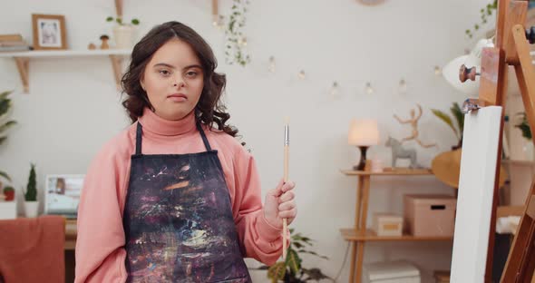 Portrait of Beautiful Little Girl with Genetic Disorder Holding Paintbrush While Standing Near