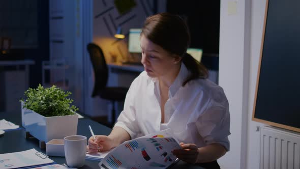 Overworked Businesswoman Writing Financial Profit on Notebook While Working in Business Company