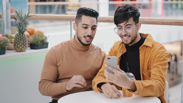 Two Happy Arab Friend Bloggers Sitting in Cafe Recording Video Blog on Phone Communicating Via