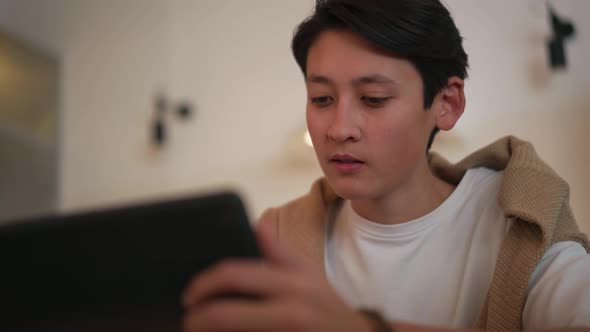 Handsome Asian man looking at tablet and drinking juice