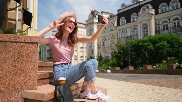 Beautiful Young Woman Tourist with Takeout Coffee Sitting on Stairs Using Smartphone