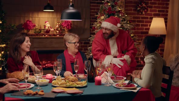 Man Disguised As Santa Claus Talking to Happy Woman at Christmas Dinner at Home