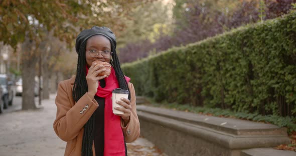 Young Black Girl with a Croissant in Her Hands in the Middle of the Street