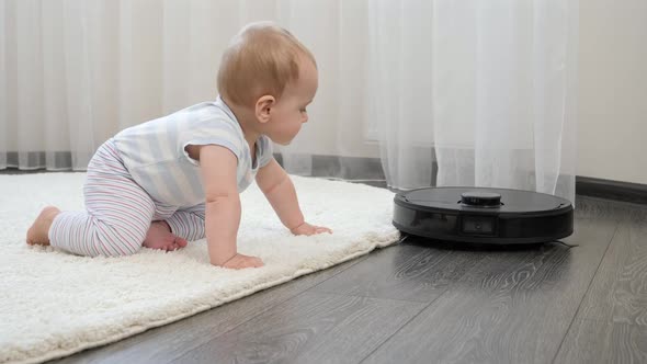 Cute Baby Boy Looking with Interest on Robot Vacuum Cleaner on Floor at Living Room