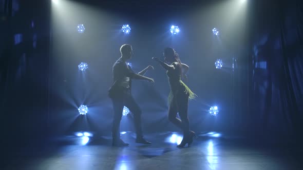 Young Couple Dancing Latin Music. Bachata, Merengue, Salsa. Shot in a Dark Studio with Neon Lights